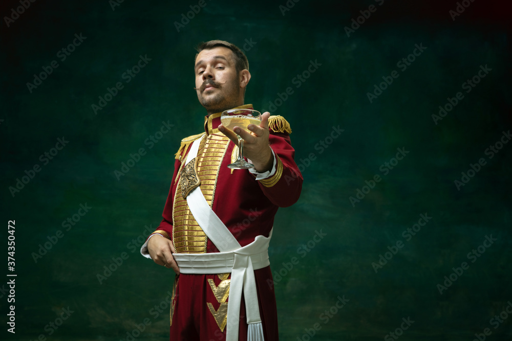 Cocktail drinking. Young man in suit as Nicholas II isolated on dark green background. Retro style, comparison of eras concept. Beautiful male model like historical character, monarch, old-fashioned. Cocktail drinking. Young man in suit as Nicholas II isolated on dark green background. Retro style, comparison of eras concept. Beautiful male model like historical character, monarch, old-fashioned.