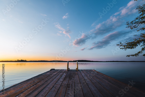 Obraz na płótnie Dock on lake at sunset with calm waters w salonie
