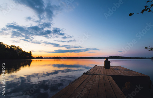 Obraz na płótnie Person sitting on dock at sunset w salonie