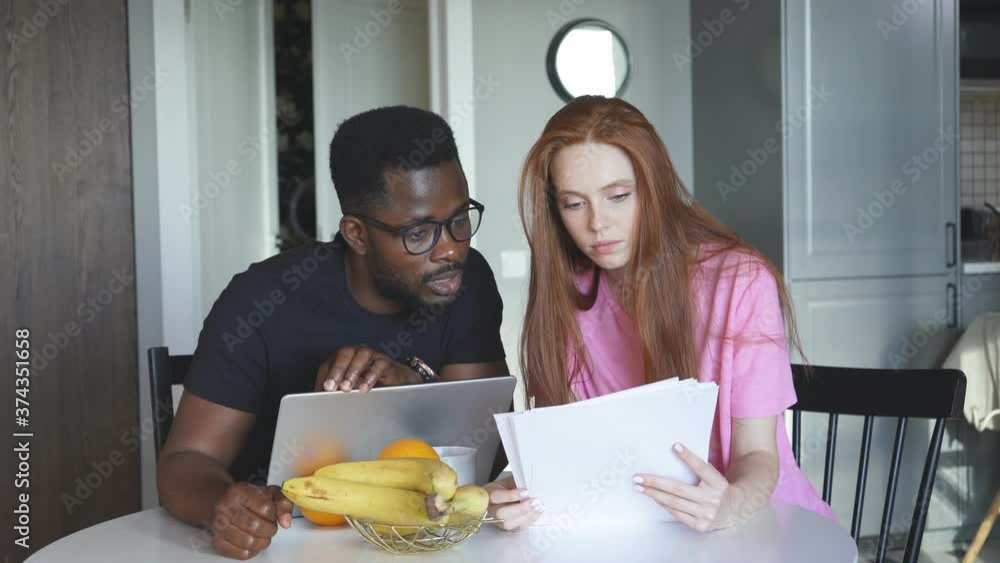 Lovely diverse man and woman check documents, discuss their plans and have conversation about mortgage or loan. Lovely diverse man and woman check documents, discuss their plans and have conversation about mortgage or loan.