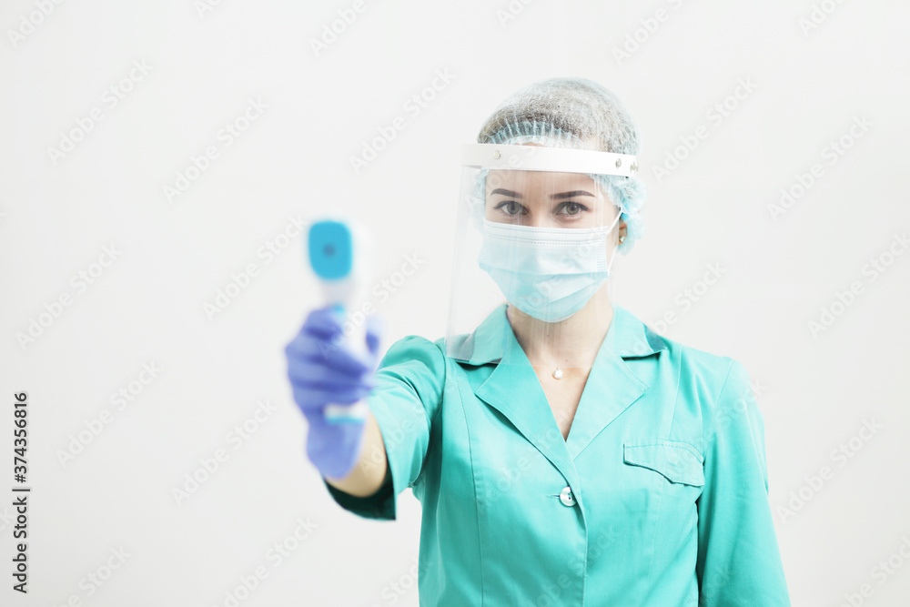 Female doctor or nurse in protective mask at hospital holds pyrometer in hand Female doctor or nurse in protective mask at hospital holds pyrometer in hand