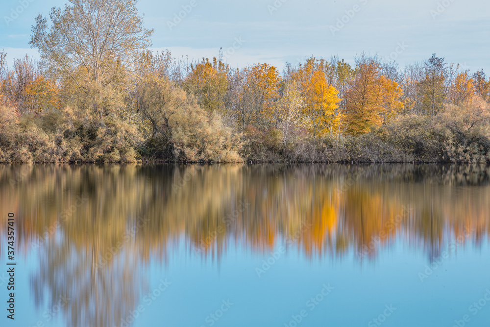 Autumn forest landscape reflection on the waters of small lake at sunset lights of sun Autumn forest landscape reflection on the waters of small lake at sunset lights of sun