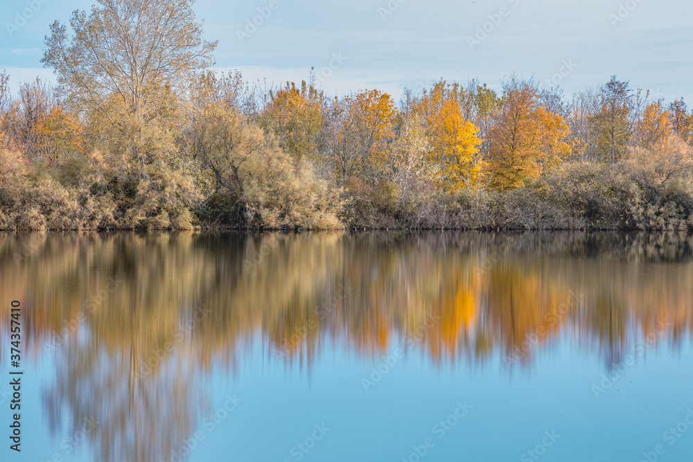 Autumn forest landscape reflection on the waters of small lake at sunset lights of sun