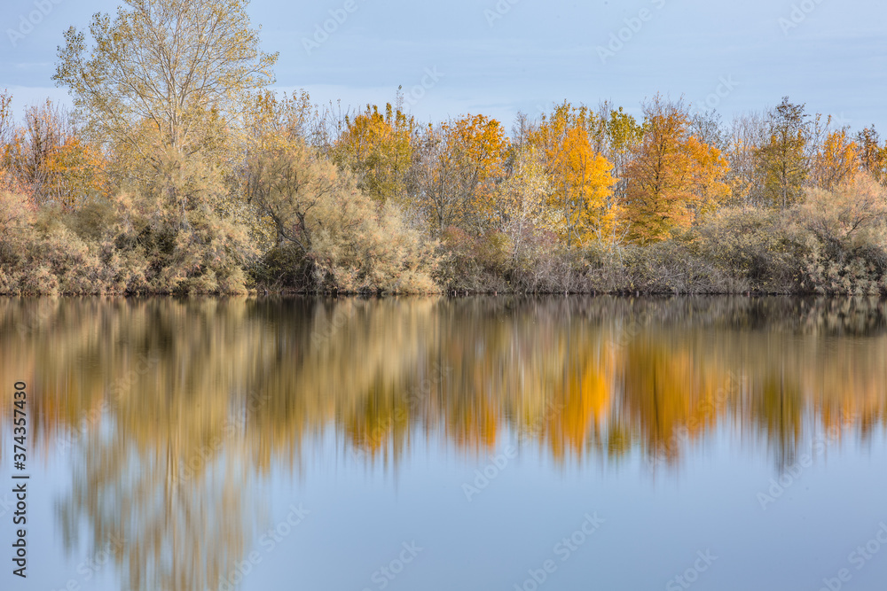 Autumn forest landscape reflection on the waters of small lake at sunset lights of sun