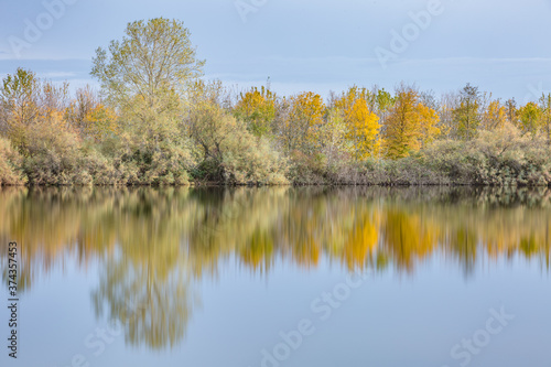Autumn forest landscape reflection on the waters of small lake at sunset lights of sun