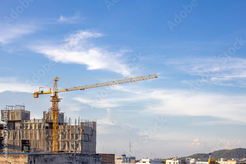 A huge crane at hotel or condo building construction site with blue sky