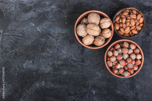 Nuts, hazelnuts, walnuts and almonds in the dishes against a dark background