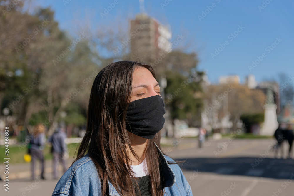 Fototapeta premium Mujer joven al sol con barbijo
