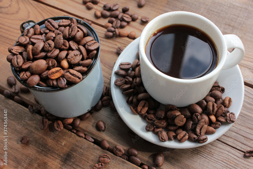 Fototapeta premium Cup of coffee with beans. Black coffee and scattered coffee beans on wooden table from above. Flat lay food composition