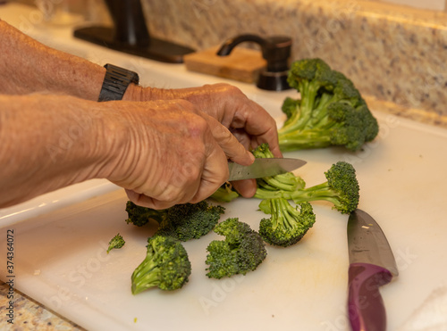 Man chopping broccoli, preparing ingredients for a delicious meal.