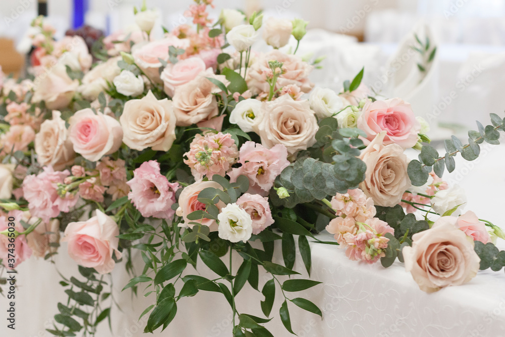 A beautiful floral arrangement in light colors is on the table with a white tablecloth.