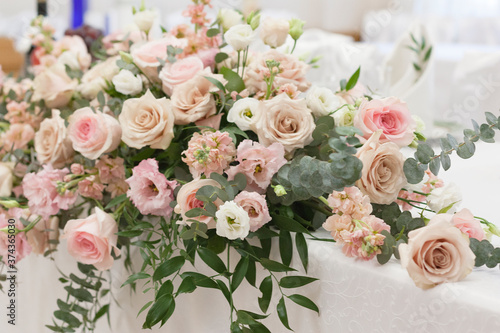 A beautiful floral arrangement in light colors is on the table with a white tablecloth. © klevers