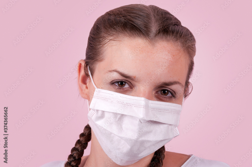 Girl in a medical mask..Girl on a pink background. The girl is protecting herself from infection. The girl put on a medical mask. Girl in a medical mask..Girl on a pink background. The girl is protecting herself from infection. The girl put on a medical mask.