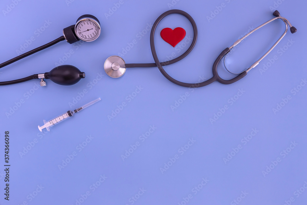 stethoscope, tonometer, syringe, red heart on a blue background. the view from the top stethoscope, tonometer, syringe, red heart on a blue background. the view from the top