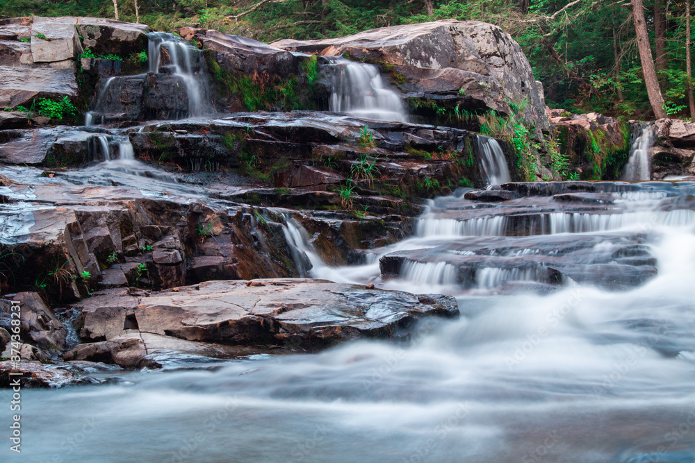 Stunning waterfalls in the middle of forest and flowing through rocky surfaces Stunning waterfalls in the middle of forest and flowing through rocky surfaces