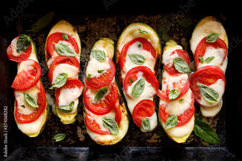 Baked zucchini stuffed caprese salad in a baking dish, top view