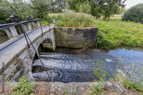 Vászonkép Keutelbeek stream with a small bridge over the dam and sluice with its black met