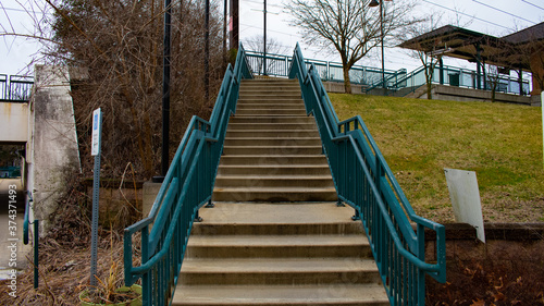 Concrete Steps Leading Up to a Train station With Blue Railings on Each Side