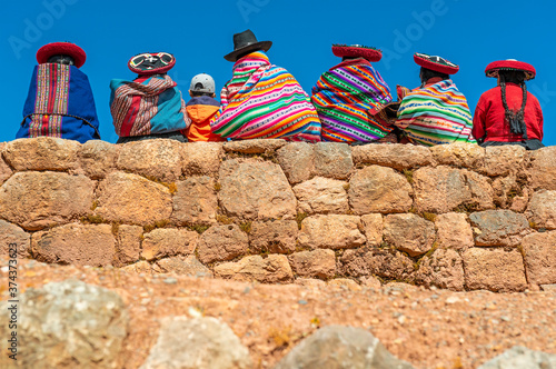 A group of Quechua indigenous women in traditional clothing with a boy sitting on an ancient Inca wall, Chinchero, Cusco, Peru. photo