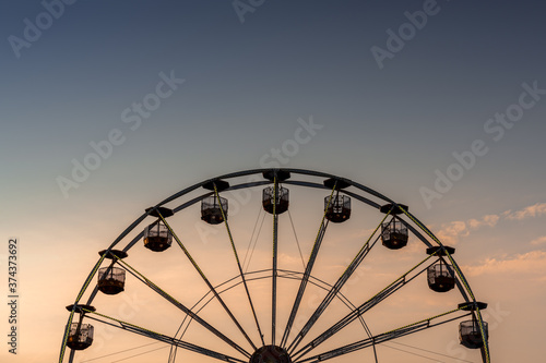 view of a ferris wheel in silhouette at sunset