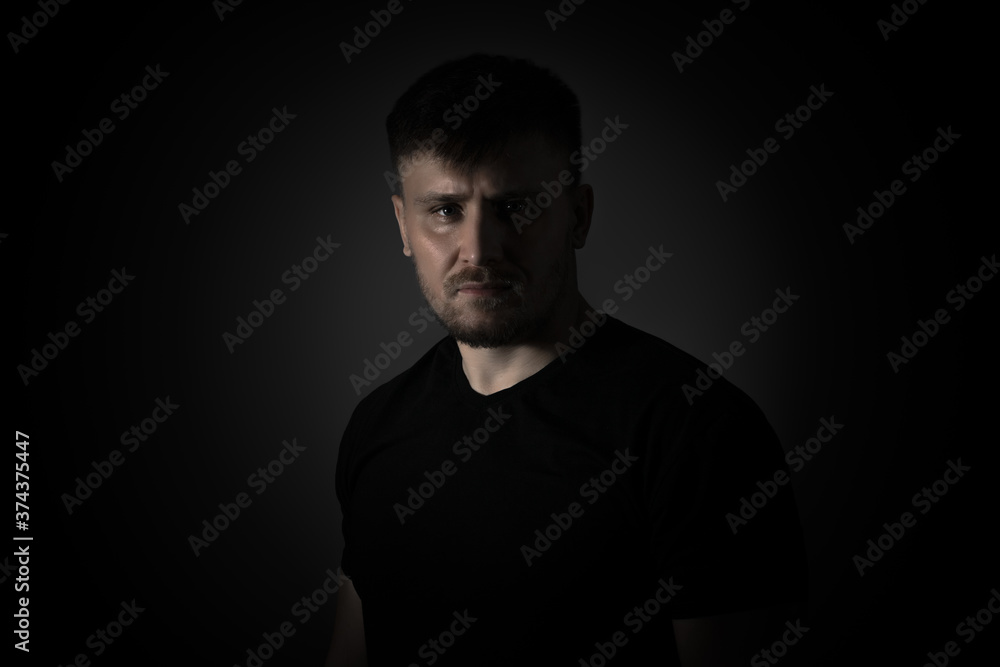 Man on a black background with a serious expression. Man on a black background with a serious expression.