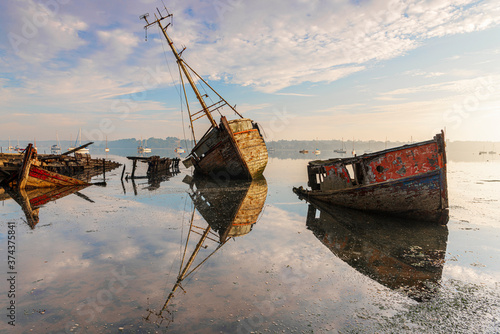 Derelict wooden boats reflected in still calm waters