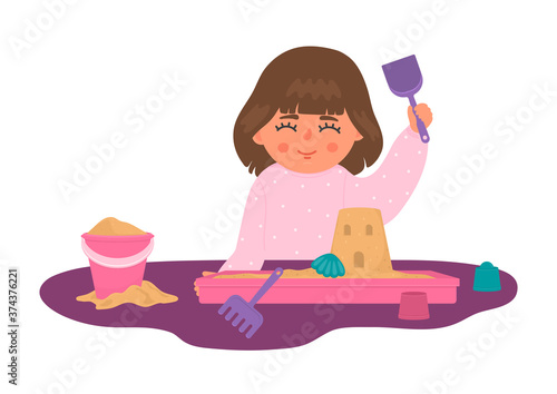 Girl plays with sand and toys in plastic sandbox on the table. Cute child builds castle at home. Children sensory, motor skills, creativity and imagination development playing concept.