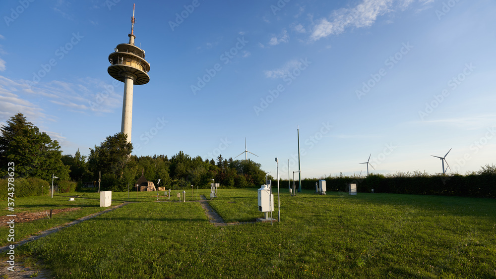 Big telecommunications and transmission tower, many measuring instruments for forecasting and recording stand on the green lawn. Germany, Schnittlingen.