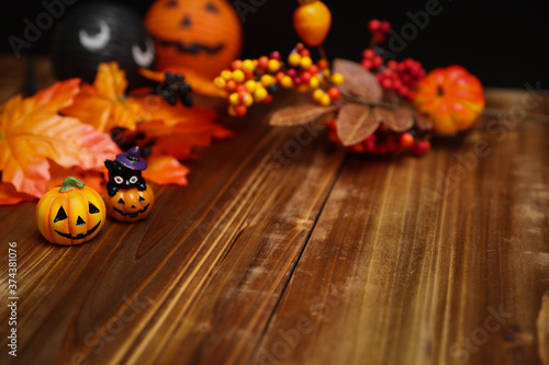 ハロウィンのイメージ素材　木目の上に置いた小さなカボチャと秋の葉や木の実の装飾