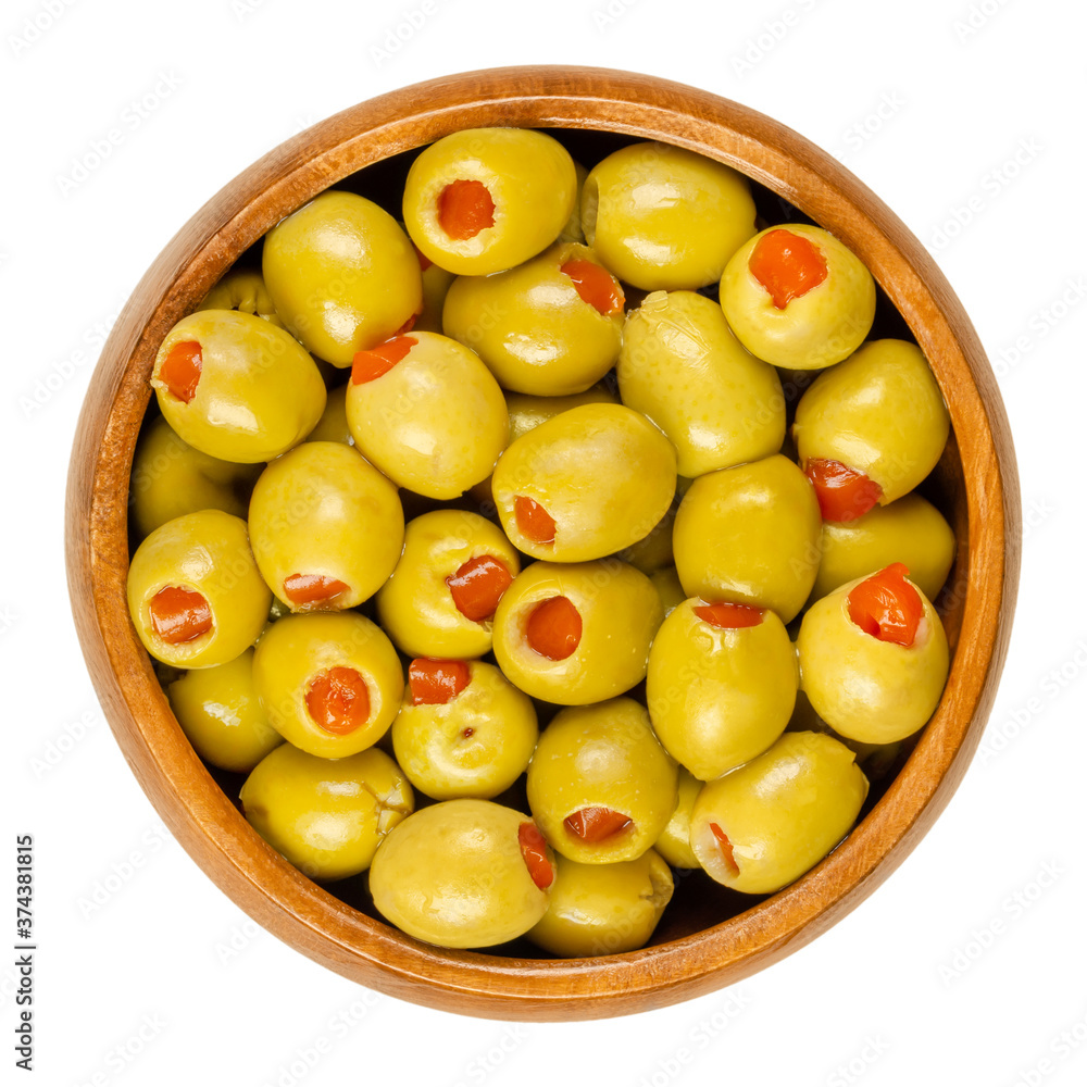 Pickled small green olives, filled with red sweet pepper in a wooden bowl. Fruits of Olea europaea, stuffed with bell pepper slices. Closeup from above, isolated on white background, macro food photo. Pickled small green olives, filled with red sweet pepper in a wooden bowl. Fruits of Olea europaea, stuffed with bell pepper slices. Closeup from above, isolated on white background, macro food photo.