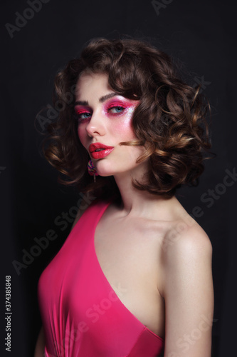 Portrait of young beautiful girl with curly hair and hot pink disco makeup