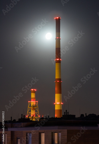 Huge industrial chimneys lit by a full moon