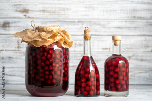 Homemade tincture of red cherry. Berry alcoholic drinks concept. Red wine made from ripe cherries in glass bottles and jars in Ukraine