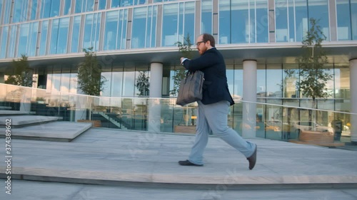 Side view of obese businessman running late for work checking time outdoors