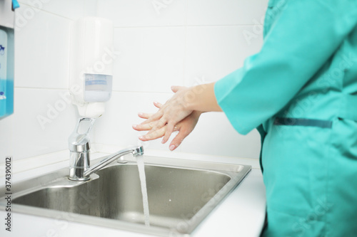 A woman doctor in protective mask washes hands thoroughly in hospital © Maksim Selin