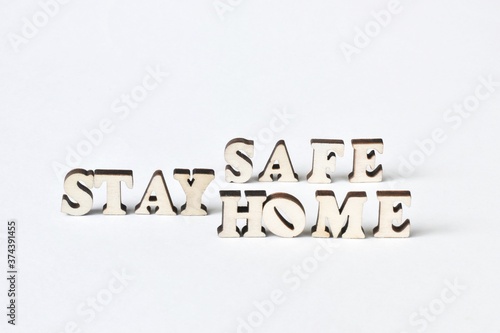 Wooden letters form "stay home, stay safe" on a white background. Health care, pandemic, virus concept.