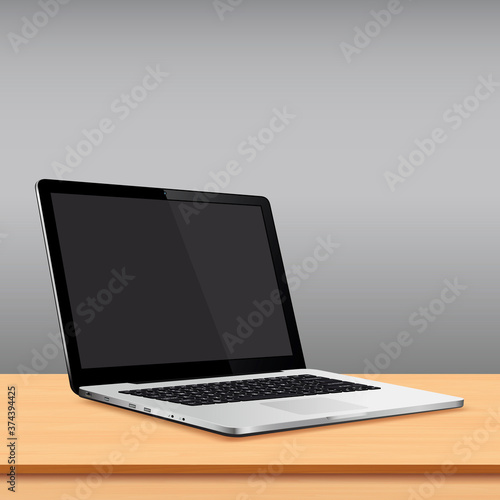 Laptop blank screen on wooden table with grey wall background