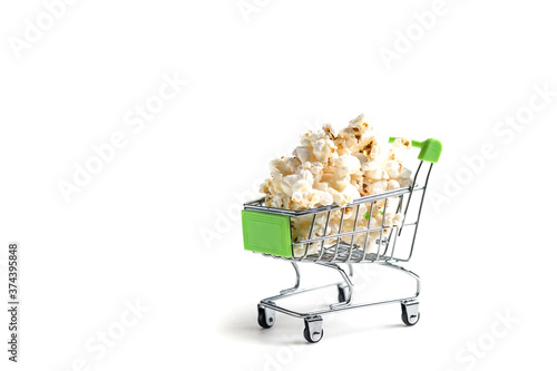 Miniature cart from the supermarket. A cart full of popcorn. Lots of popcorn isolated on a white background.