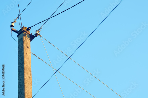 Power line post with electric cables against a clear sky. Power lines