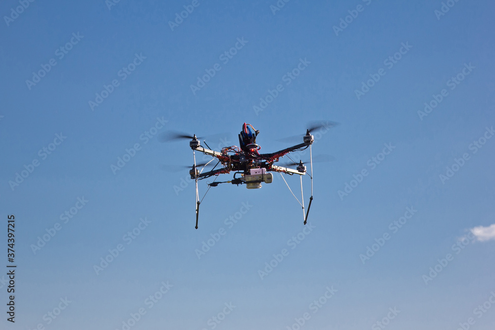Flying handmade drone on blue sky background Flying handmade drone on blue sky background