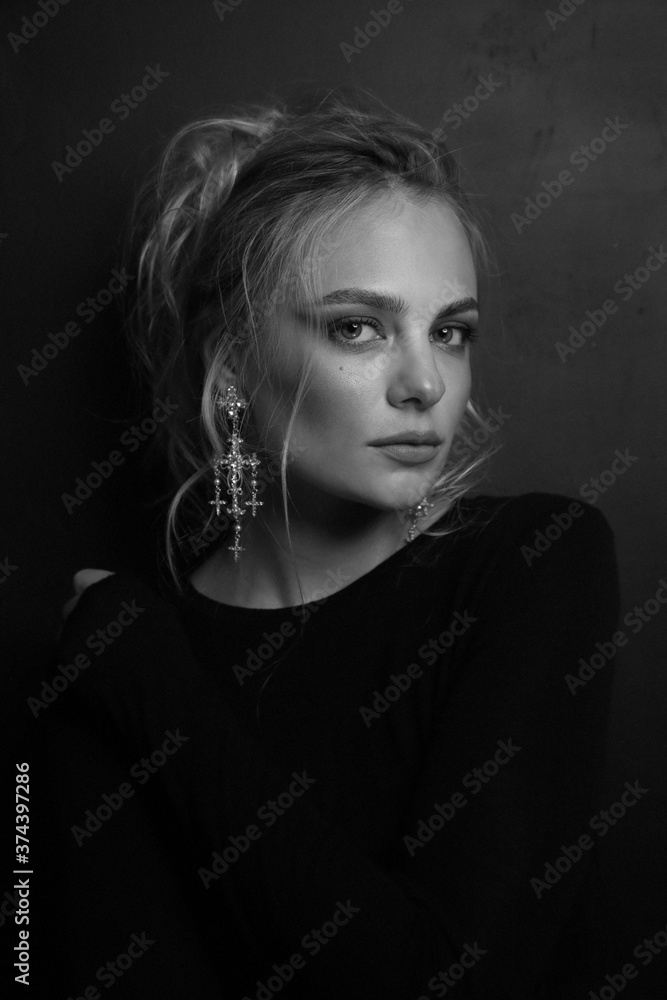 Vintage style grainy black and white portrait of young beautiful woman with prom hairdo and fancy earrings