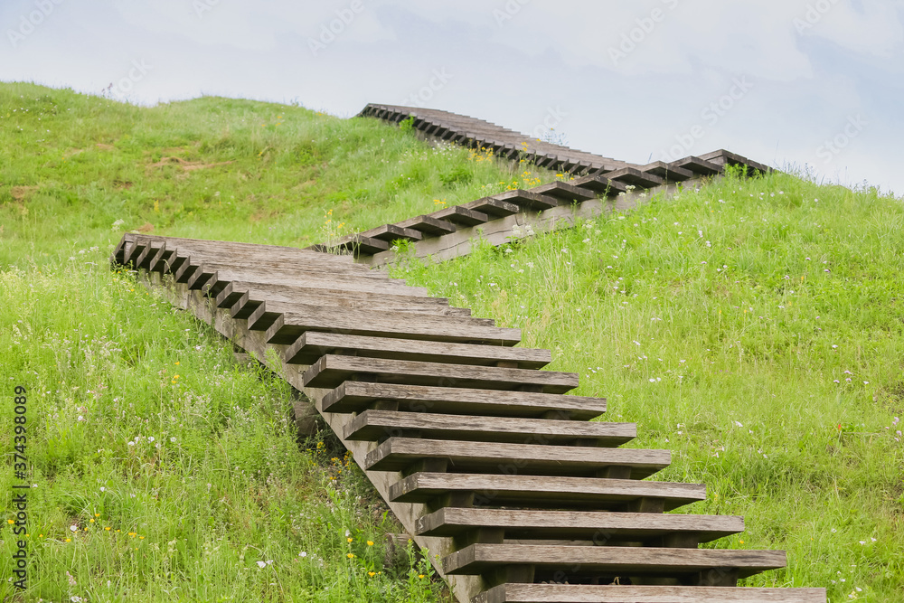 A green Zig Zag stairs uphill. Concept growth on grass