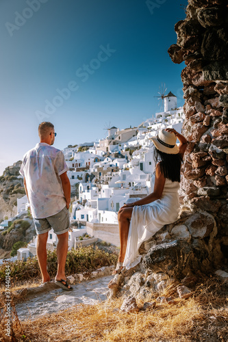 Santorini Greece, young couple on luxury vacation at the Island of Santorini watching sunrise by the blue dome church and whitewashed village of Oia Santorini Greece during sunrise during summer photo