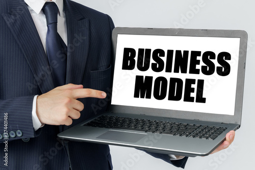 A businessman holds a laptop in his hands and shows on the screen with the text - BUSINESS MODEL