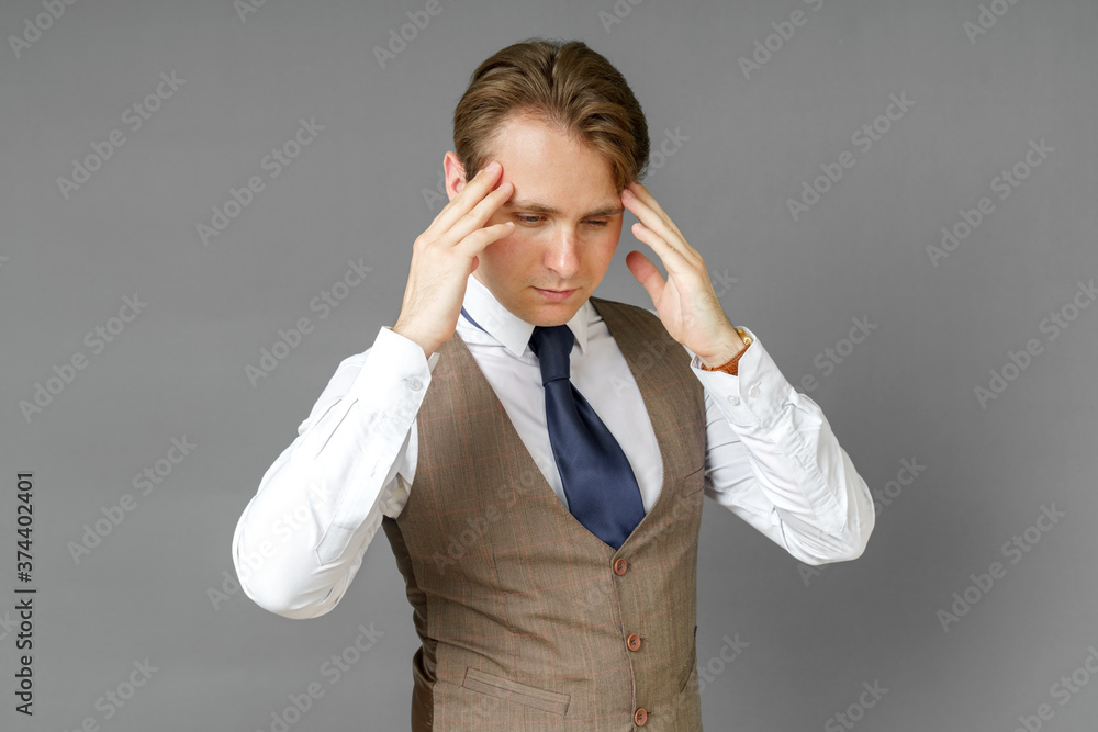 An emotional portrait of a businessman who touches his head with his hands. Gray background An emotional portrait of a businessman who touches his head with his hands. Gray background