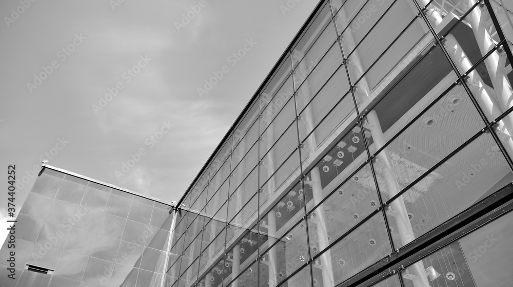 Obraz premium Modern office building wall made of steel and glass with blue sky. Black and white.