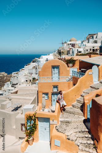 Santorini Greece, young man on luxury vacation at the Island of Santorini watching sunrise by the blue dome church and whitewashed village of Oia Santorini Greece during sunrise during summer vacation photo