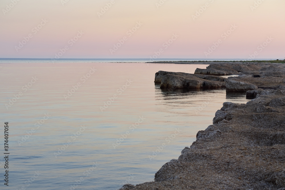 Sunset at the sea with calm water, on the coast on which mountains of dead algae pile up Sunset at the sea with calm water, on the coast on which mountains of dead algae pile up