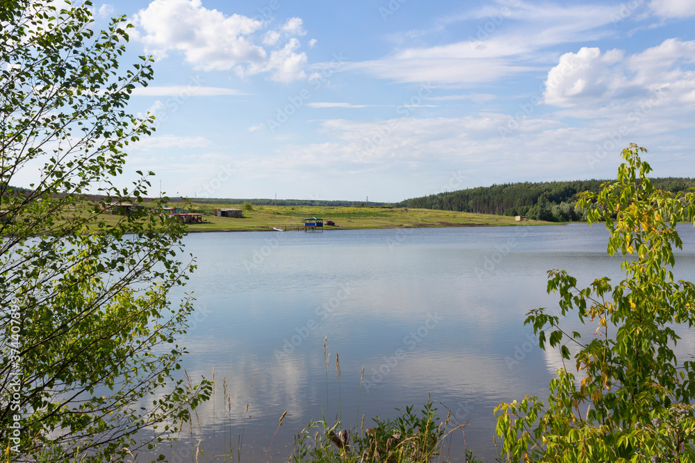 A pond near the village of Terentievka in the Ulyanovsk region on a sunny summer day, forest, shore, reflection of clouds in the water, the beauty of a traditional summer Russian landscape