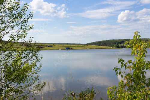 Fototapeta Naklejka Na Ścianę i Meble -  A pond near the village of Terentievka in the Ulyanovsk region on a sunny summer day, forest, shore, reflection of clouds in the water, the beauty of a traditional summer Russian landscape